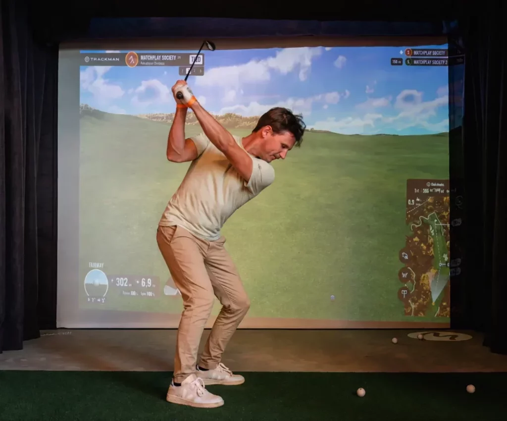 homme levant le club de golf devant simulateur